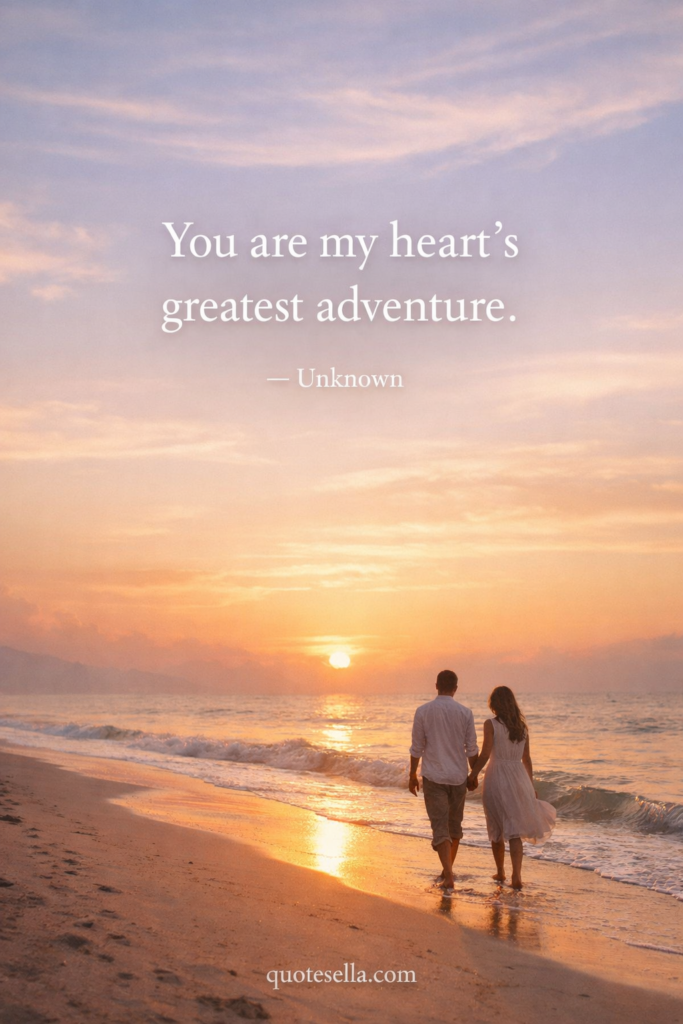 Couple walking hand in hand along the beach at sunset with pastel sky and ocean waves, featuring the quote “You are my heart’s greatest adventure” attributed to Unknown and quotesella.com at the bottom.
